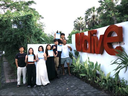 UDive Bali students with Open Water certificates at the UDive sign